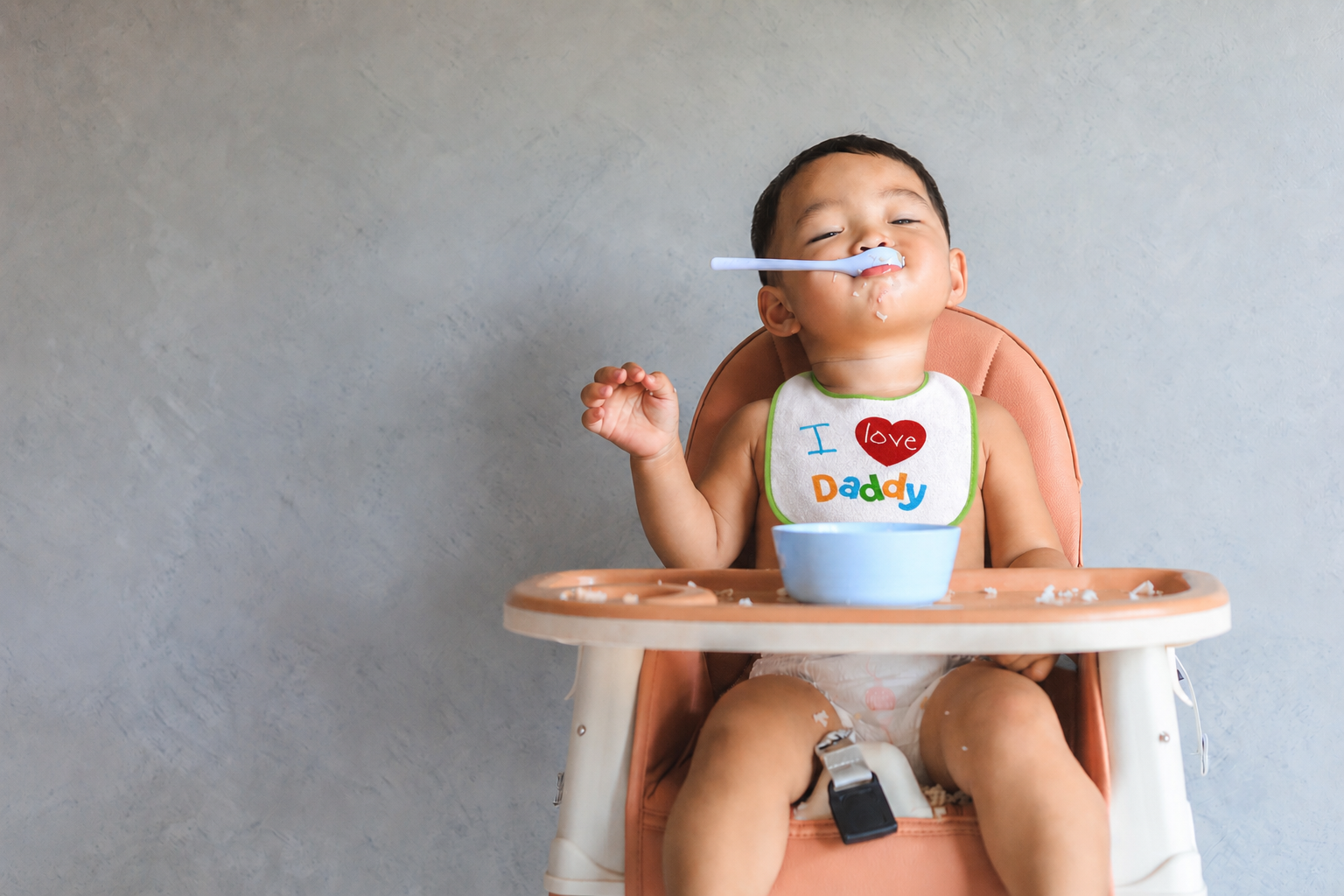 Baby in a high chair wearing a Baby King bib
